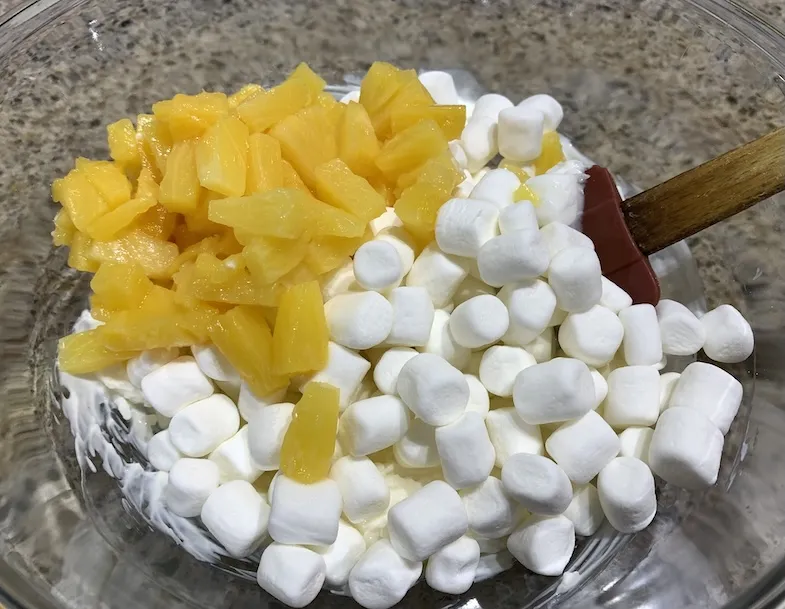 adding marshmallows and pineapple to the Ambrosia Salad