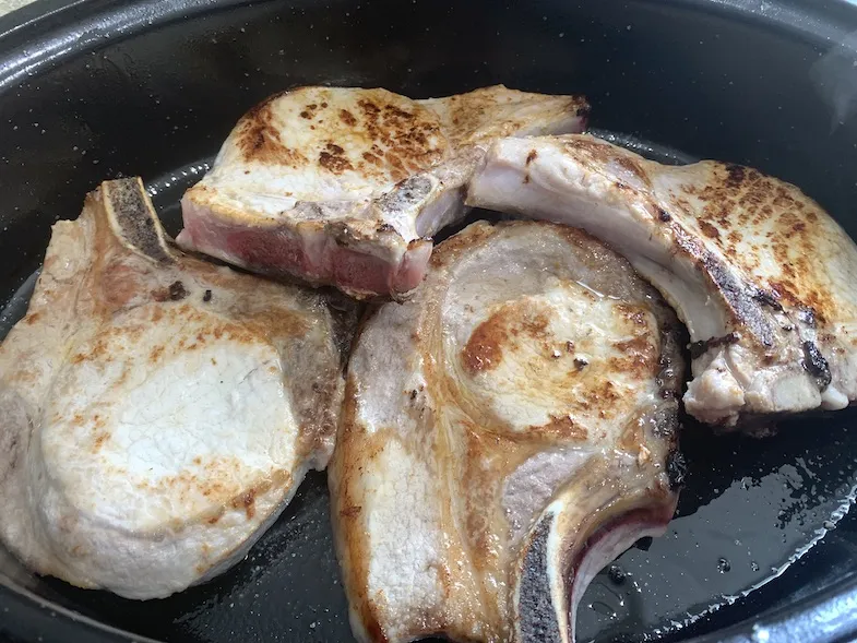 pork chops browning in a frying pan