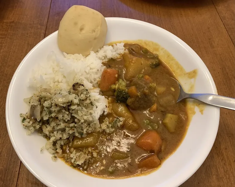 bowl of gluten-free coconut beef curry with rice, fried cauliflower rice and a O'dough's gluten-free pita bread