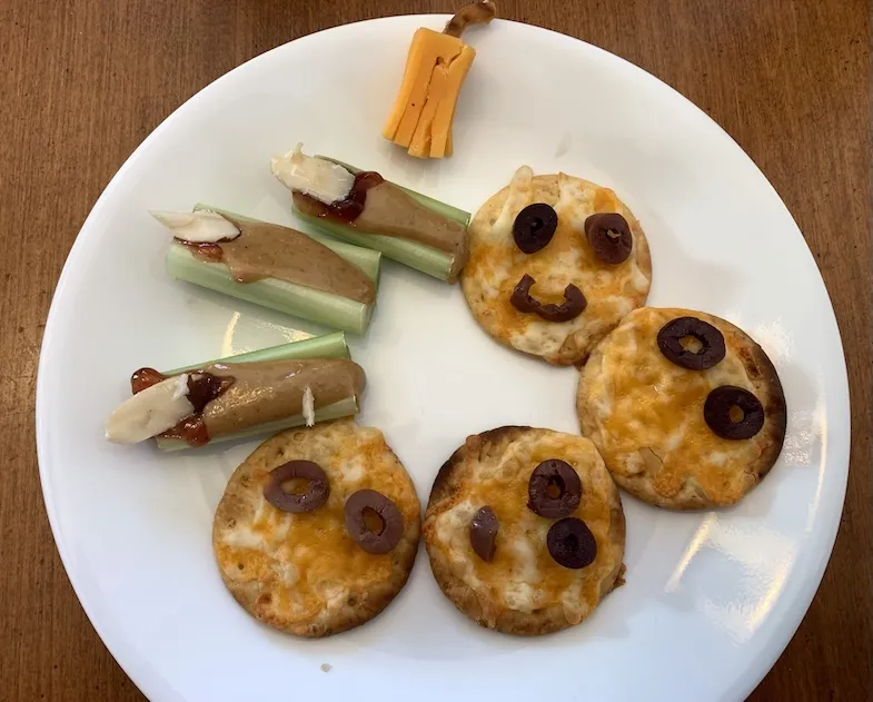 gluten-free Halloween crackers, witches fingers and cheese pretzel broom on a plate