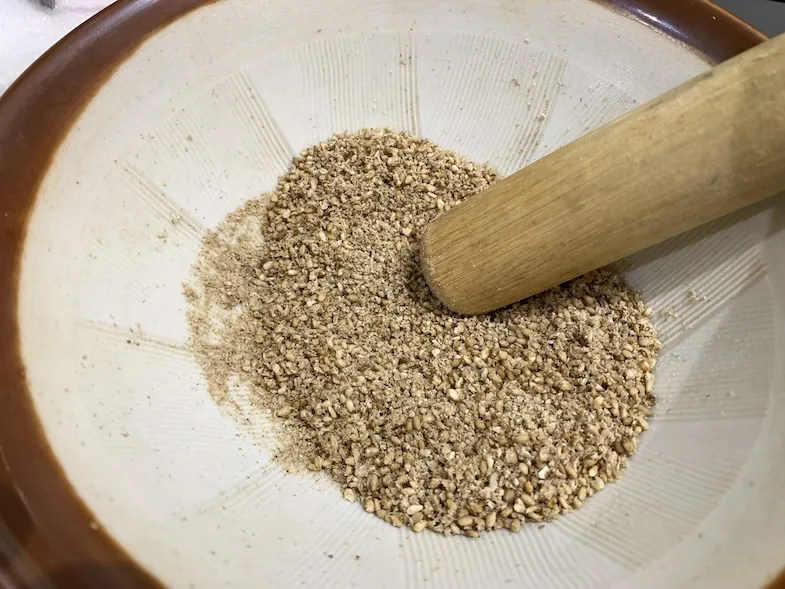 grinding toasted sesame seeds in a suribachi