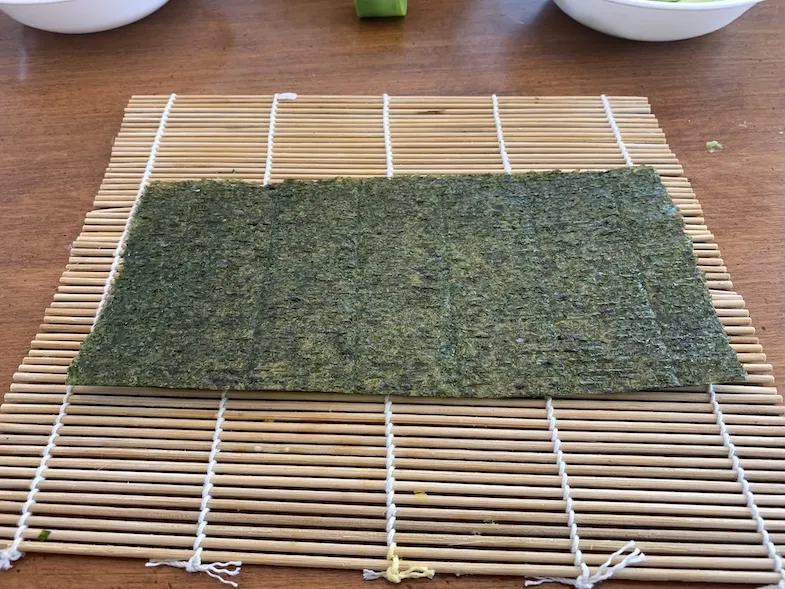 half a nori sheet on a bamboo rolling mat