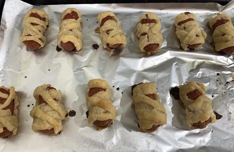 baked gluten-free wrapped mummy hot dogs on baking tray