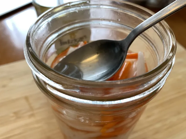 pushing the vegetables down into the vinegar dressing