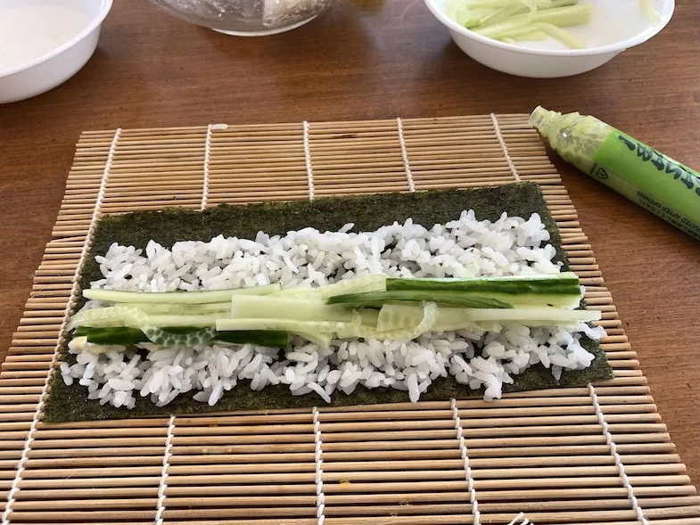 adding cucumber strips to the half sushi roll